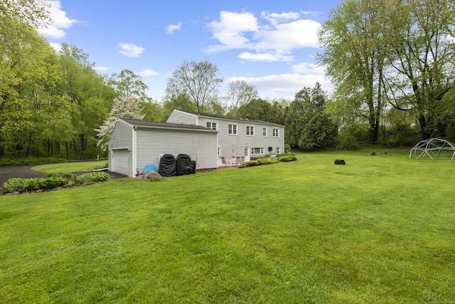 back of property with a lawn, a garage, and view of wooded area