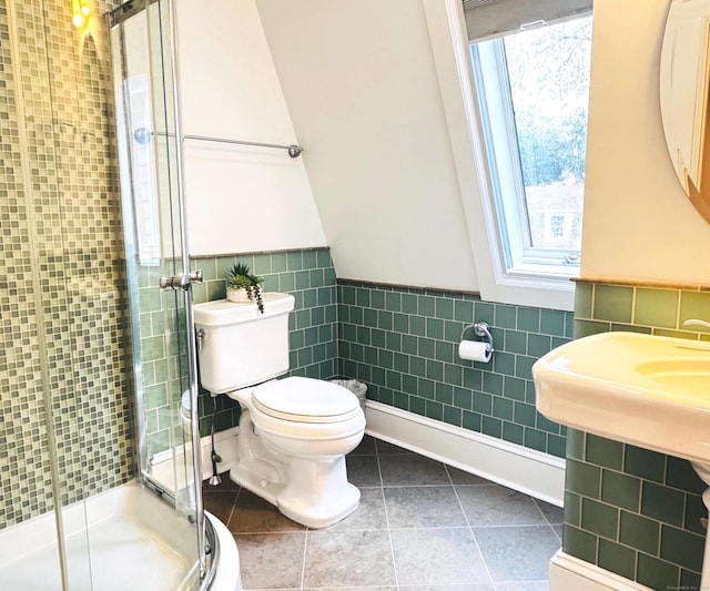 bathroom with toilet, a wainscoted wall, tile walls, tile patterned flooring, and a shower stall