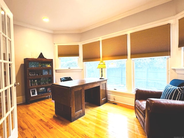 office area with ornamental molding, baseboards, light wood-type flooring, and visible vents