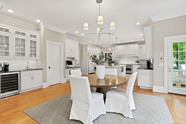 dining room featuring recessed lighting, light wood-style floors, crown molding, and beverage cooler