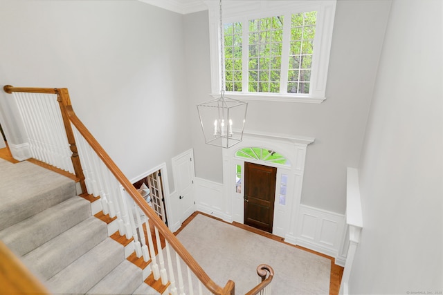 foyer entrance with a notable chandelier, a decorative wall, a wainscoted wall, and wood finished floors
