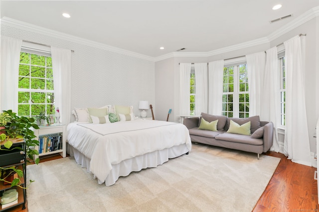 bedroom with multiple windows, visible vents, wallpapered walls, and wood finished floors