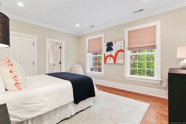 bedroom with wood finished floors, crown molding, visible vents, baseboards, and recessed lighting