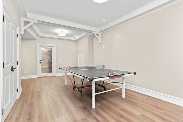 recreation room featuring baseboards, ornamental molding, and light wood-type flooring