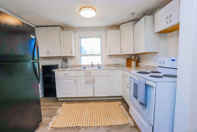 108 New Litchfield St, Torrington, CT 06790 - kitchen featuring electric range, freestanding refrigerator, light countertops, white cabinets, and a textured ceiling