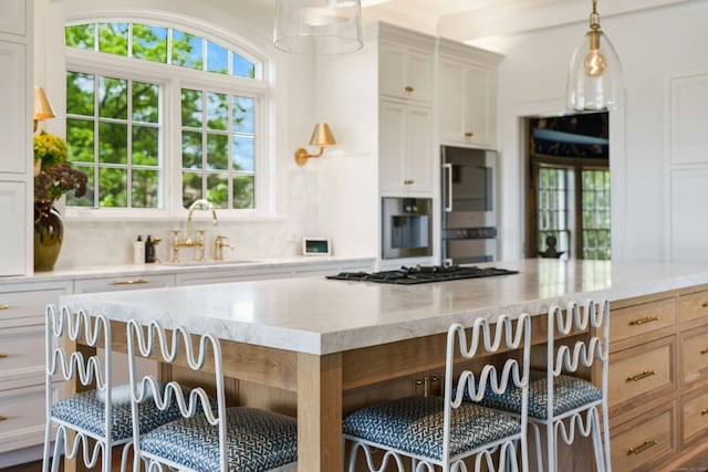 25 Tokeneke Trl, Darien, CT 06820 - kitchen with a sink, light stone counters, pendant lighting, white cabinets, and gas cooktop