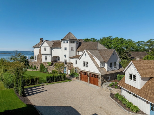 25 Tokeneke Trl, Darien, CT 06820 - shingle-style home with stone siding, an attached garage, gravel driveway, a chimney, and a water view