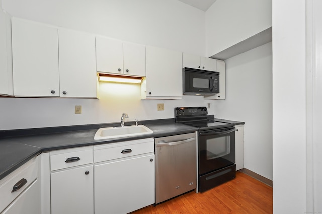 kitchen with a sink, light wood-style flooring, black appliances, and dark countertops