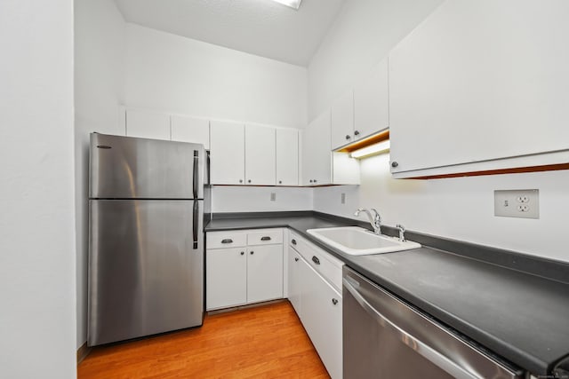 kitchen with a sink, white cabinets, dark countertops, and stainless steel appliances