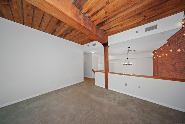 empty room featuring a notable chandelier, beam ceiling, carpet floors, baseboards, and visible vents