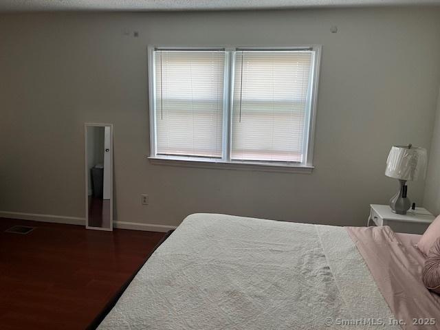 57 Meetinghouse Vlg Unit 6, Meriden, CT 06450 - bedroom featuring baseboards, wood finished floors, visible vents, and multiple windows