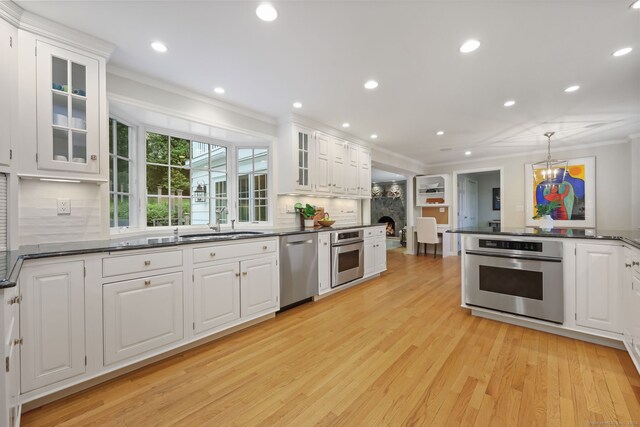 6 Weathervane Hl, Westport, CT 06880 - kitchen with stainless steel appliances, crown molding, a sink, light wood-style flooring, and white cabinets