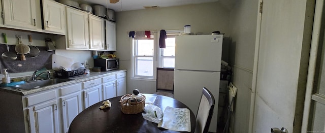 324 Mountain Grove St, Bridgeport, CT 06605 - kitchen with freestanding refrigerator, stainless steel microwave, a sink, and white cabinets