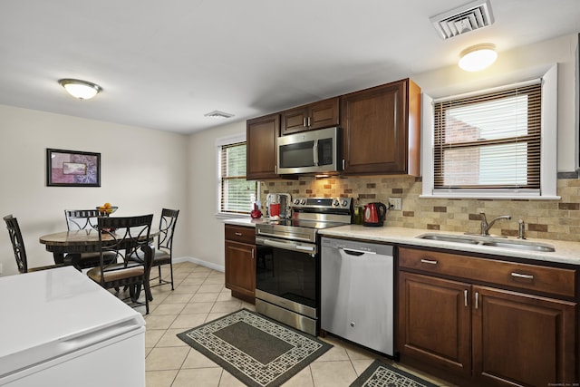 201 Orchard Ave, Newington, CT 06111 - kitchen featuring stainless steel appliances, light countertops, decorative backsplash, light tile patterned floors, and dark brown cabinets