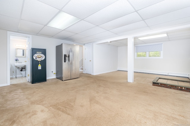 below grade area featuring a paneled ceiling, light carpet, and stainless steel fridge with ice dispenser
