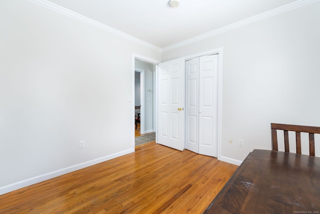 unfurnished bedroom featuring crown molding, a closet, baseboards, and light wood-type flooring