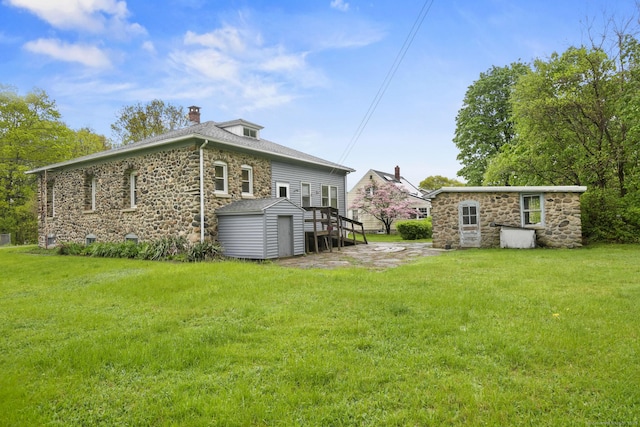 298 Wall St, Waterbury, CT 06704 - back of property with stone siding, an outdoor structure, and a yard