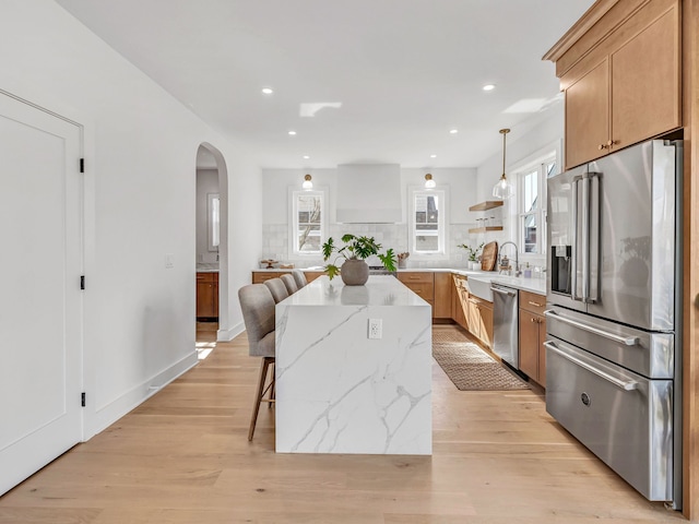 13 Dunbar Rd, Milford, CT 06460 - kitchen featuring a kitchen island, light wood-type flooring, arched walkways, a sink, and appliances with stainless steel finishes