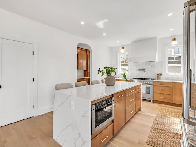 13 Dunbar Rd, Milford, CT 06460 - kitchen with decorative backsplash, a kitchen island, high end appliances, arched walkways, and custom range hood