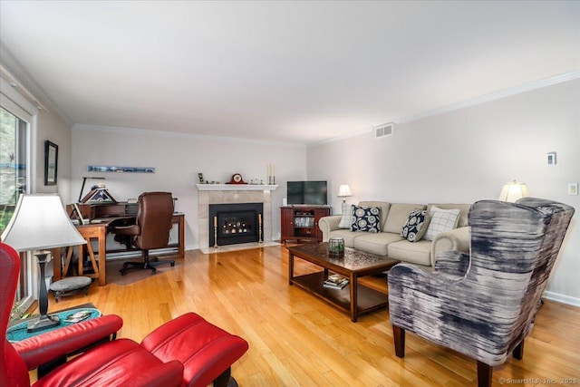 28D Harbour Vlg, Branford, CT 06405 - living room featuring light wood finished floors, ornamental molding, a tiled fireplace, and baseboards