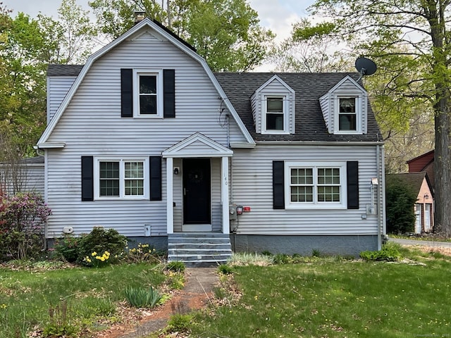dutch colonial featuring a front lawn and roof with shingles