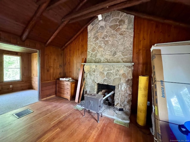 unfurnished living room with visible vents, wood walls, hardwood / wood-style floors, and vaulted ceiling with beams