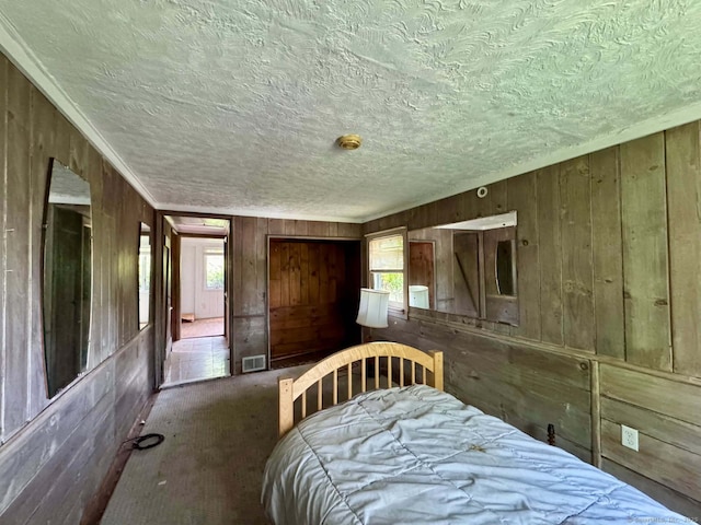 carpeted bedroom featuring wooden walls, visible vents, and multiple windows
