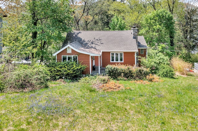 view of front of house with roof with shingles, a front lawn, and a chimney
