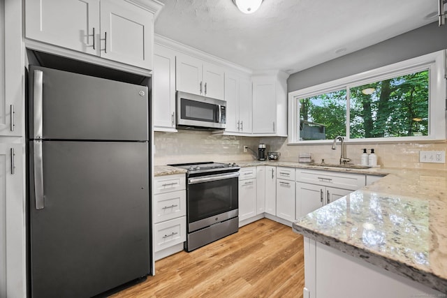 333 Vincellette St Unit 25, Bridgeport, CT 06606 - kitchen featuring appliances with stainless steel finishes, a sink, white cabinetry, light wood-style flooring, and decorative backsplash