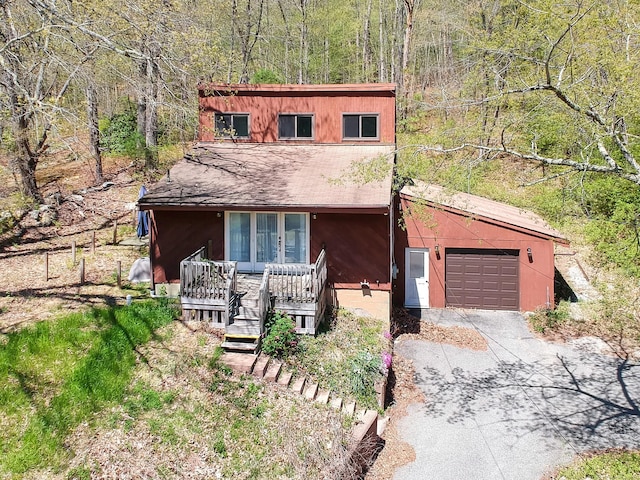 view of front of home featuring a garage, a view of trees, and concrete driveway
