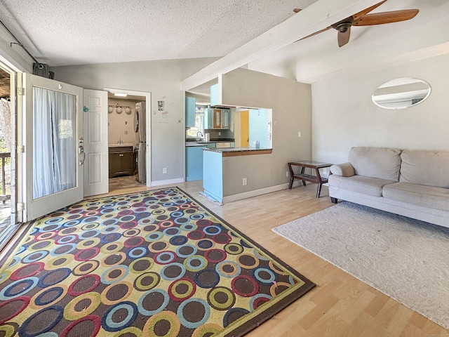 living room featuring light wood-style floors, a textured ceiling, plenty of natural light, and ceiling fan