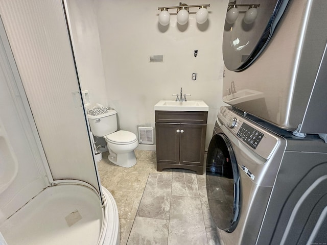 bathroom featuring stacked washer / drying machine, vanity, toilet, a shower stall, and visible vents