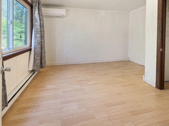 empty room with light wood-type flooring, an AC wall unit, and a healthy amount of sunlight