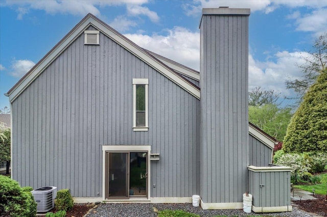 back of house featuring a chimney and central AC unit