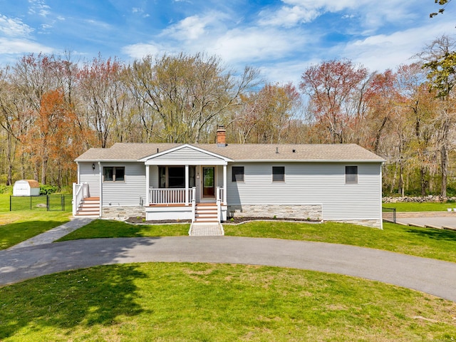 view of front of home featuring a chimney, fence, covered porch, and a front yard
