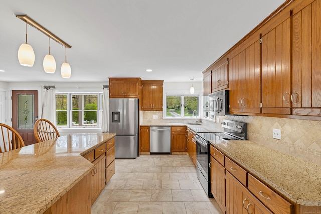 kitchen featuring stone finish floor, brown cabinetry, appliances with stainless steel finishes, tasteful backsplash, and light stone counters