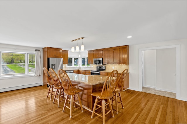 kitchen with light wood-type flooring, a wealth of natural light, and stainless steel appliances