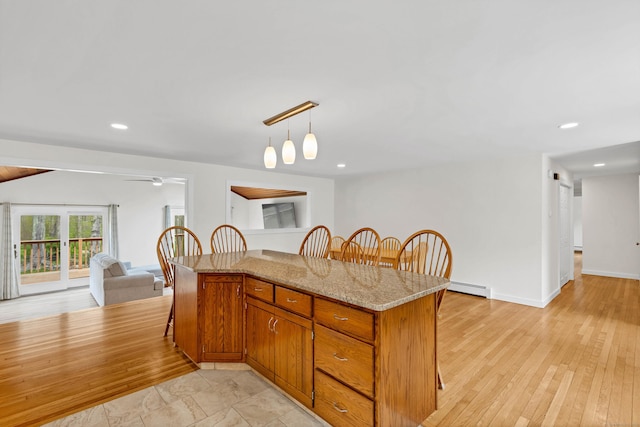 kitchen featuring brown cabinetry, pendant lighting, open floor plan, a breakfast bar area, and baseboard heating