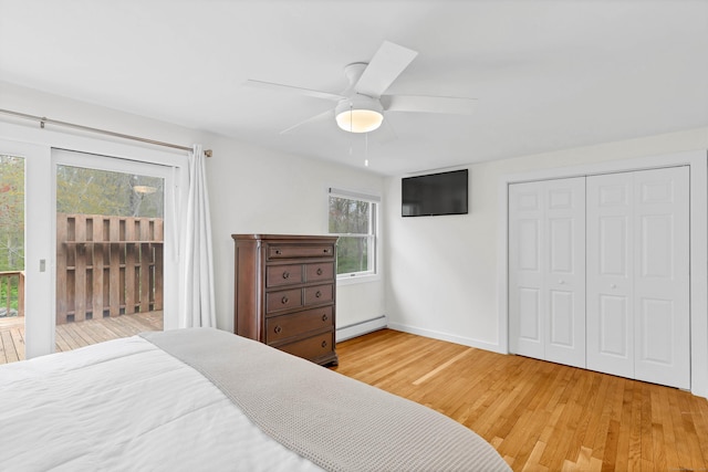 bedroom featuring access to outside, a ceiling fan, wood finished floors, a baseboard heating unit, and a closet