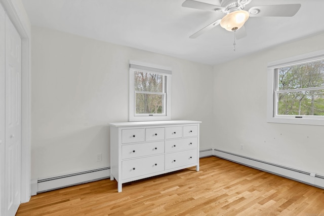 unfurnished bedroom with a baseboard radiator, light wood-style flooring, and ceiling fan