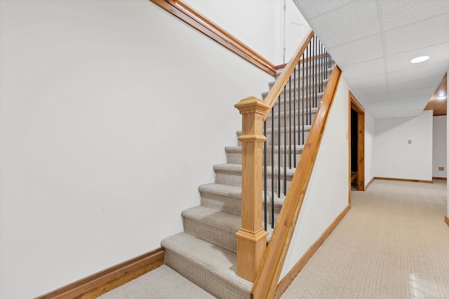 stairway with baseboards, carpet flooring, and a paneled ceiling