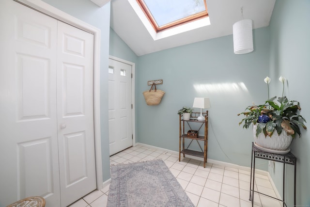 entrance foyer with light tile patterned flooring, baseboards, and lofted ceiling with skylight