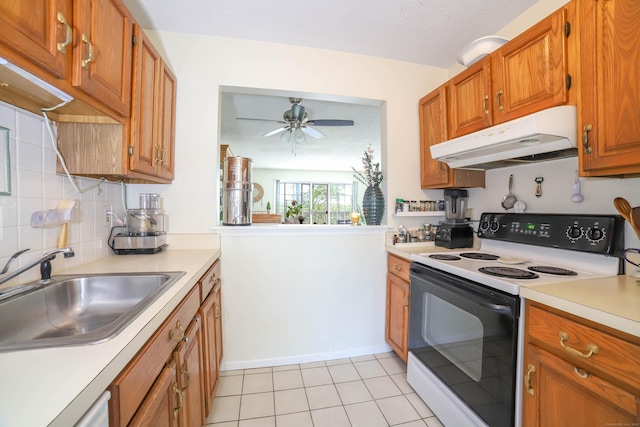 kitchen featuring under cabinet range hood, electric range oven, a sink, brown cabinets, and light countertops