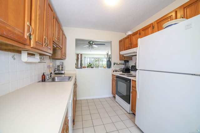 kitchen with freestanding refrigerator, under cabinet range hood, a sink, electric stove, and light countertops