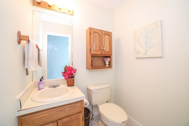 half bath with toilet, tile patterned floors, and vanity