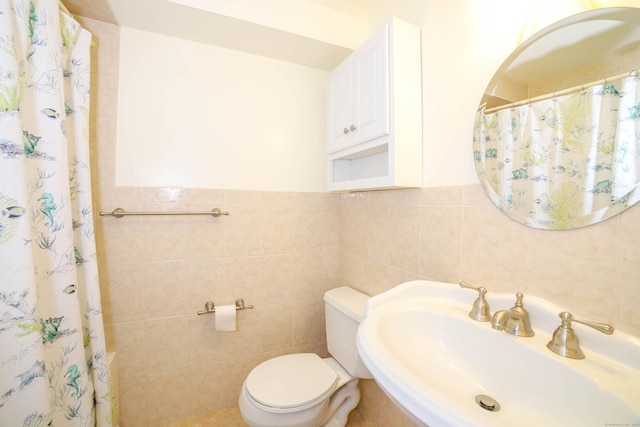 full bathroom featuring a sink, toilet, and tile walls