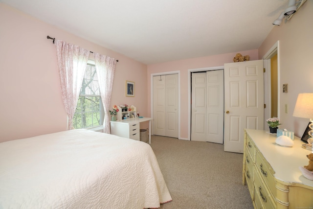 bedroom featuring two closets and light colored carpet