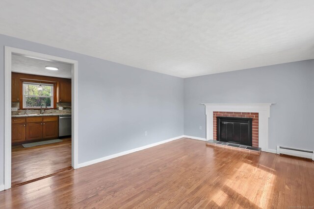327 Abbe Rd, Enfield, CT 06082 - unfurnished living room featuring a brick fireplace, baseboards, wood finished floors, and a baseboard radiator