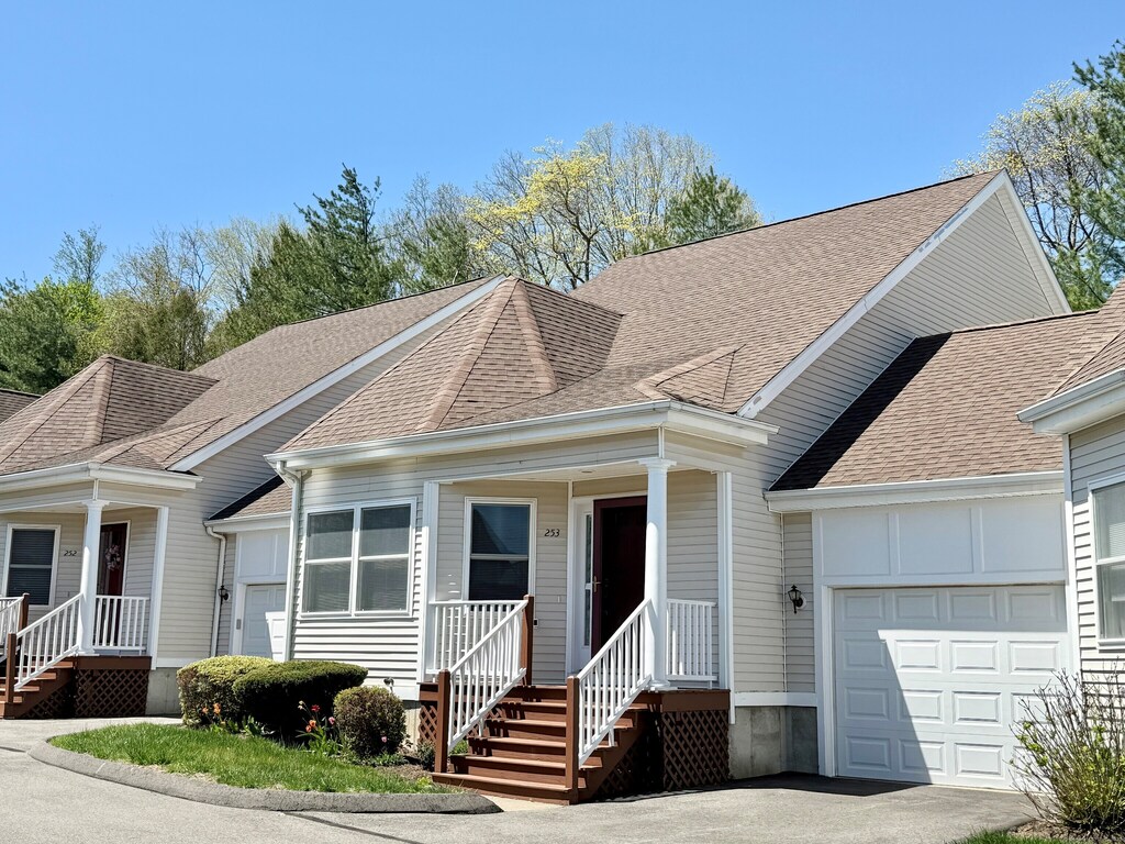 view of front of house featuring a porch, an attached garage, roof with shingles, and aphalt driveway