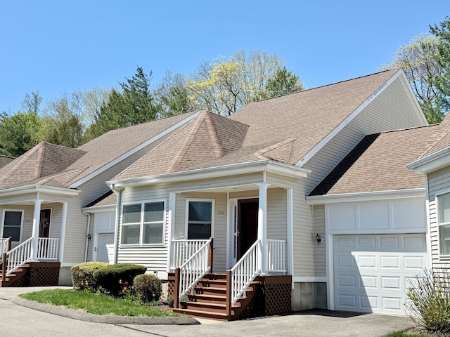 view of front of house featuring a porch, an attached garage, roof with shingles, and aphalt driveway